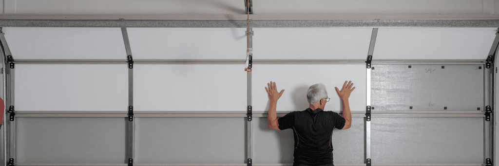 Installer pressing ThermaDoor insulation panel into place on a sectional garage door